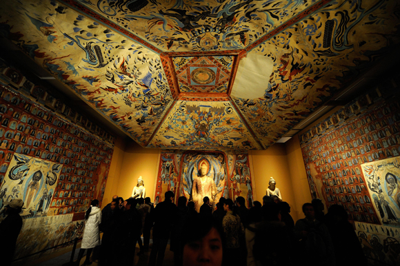 Visitors visit a replica parts of the Mogao Cave during the Dunhuang Art Exhibition in Beijing on February 20, 2008.  The exhibition displays collections mostly from the Dunhuang Grottoes which were constructed between the 4th and the 14th century, including recovered antres, original painted sculptures and their replicas from Library Cave of Dunhuang. Dunhuang, located in Jiuquan of Northwest China's Gansu province along the historic Silk Road, is in danger of being swallowed by sands of the adjacent Kumtag desert, which are creeping closer at a rate of up to four metres (13 feet) a year. (Photo credit TEH ENG KOON/AFP/Getty Images)