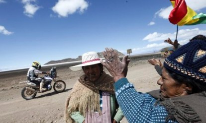 A Dakar rally competitor passes indigenous people between Bolivia and Chile. The rally, it is claimed, turns their land into a tourist attraction. Photo: Felipe Trueba/EPA