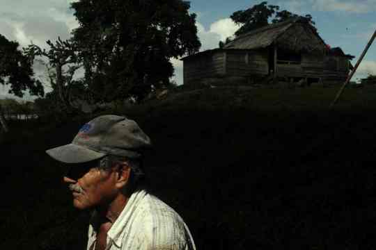 A farmer stands near his home beside a river in Monkey Point. Details of the canal remain unknown across the country; even people who may be displaced by its construction are unsure what’s in store.