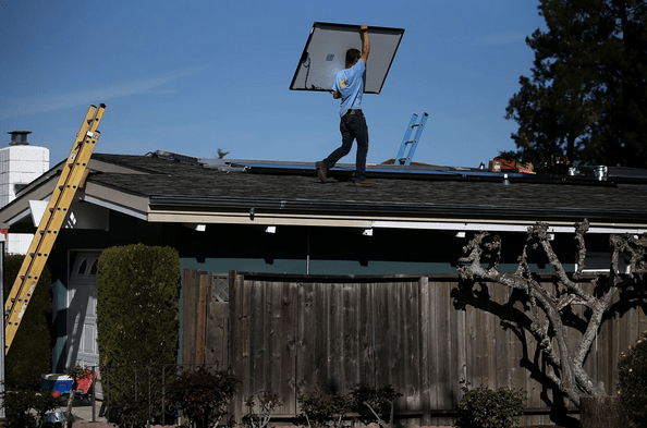 SolarCraft worker Craig Powell carries a solar panel on the roof of a home in San Rafael, Calif. The average price of photovoltaic cells has plummeted 60 percent since 2010. (Justin Sullivan/Getty Images)