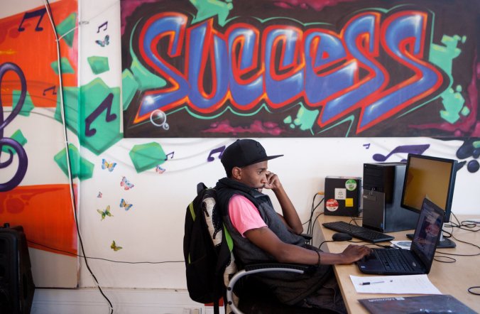 An entrepreneur uses his laptop near graffiti-decorated walls at Hubspace in the Khayelitsha township. Emily Jan/NPR