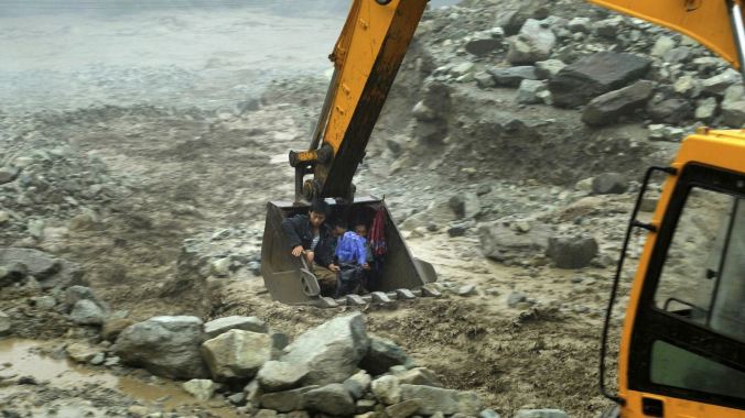 An excavator moves villagers away from a flooded area in Sichuan province in July, 2013. PHOTO: Reuters