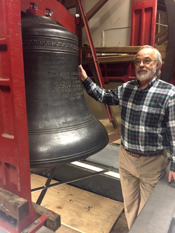 Tony Furnivall beside one of the dozen bells in Trinity Church's clocktower. (Photo: Ella Morton)