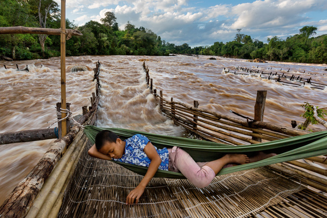 In southern Laos, near where the Don Sahong dam will soon rise, a fisherman’s son snoozes above his father’s weir, waiting for fish migrating upstream to tire and wash back into the trap. PHOTO: David Guttenfelder