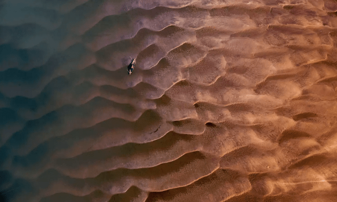 The shot was taken on the bank of Padma River in Bera, Pabna. It was evening, so I got the beautiful golden rays of the sun playing over the sandy texture of the riverbank. The lone boat reminded me of my childhood days when I used to ride a boat on the river.